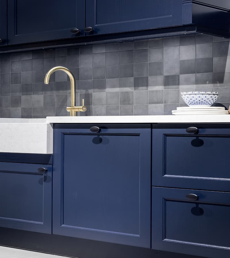 Donkerblauwe keuken met licht werkblad en gouden kraan