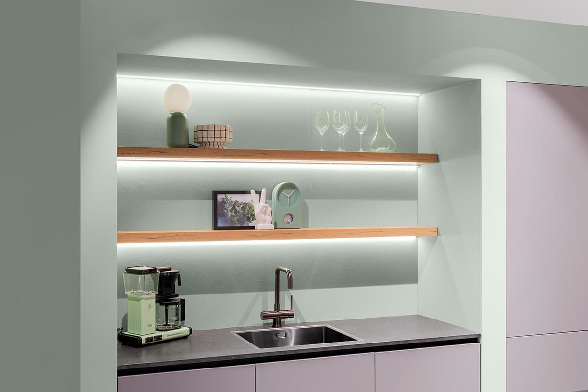 Lichtgrijze keuken met houten wandplankjes en pastelgroene muur